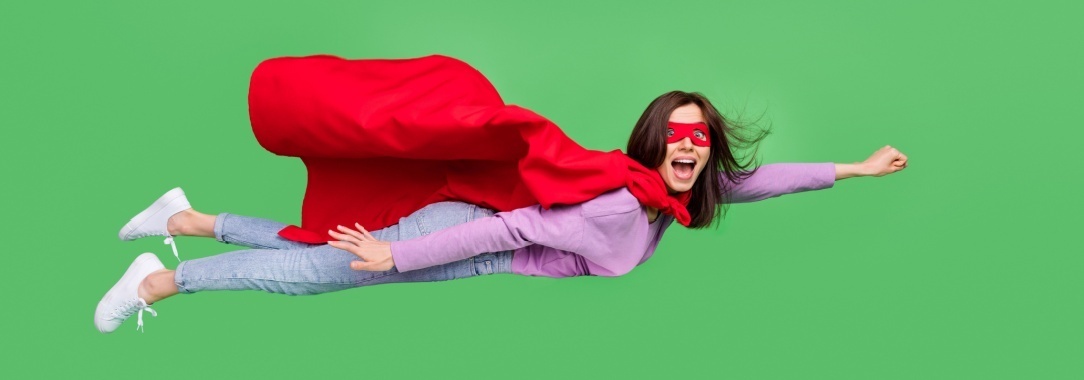 A photo of a very happy woman wearing a red cape flying against a green background 