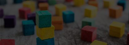 An image of colorful wooden building blocks on a grey wooden surface